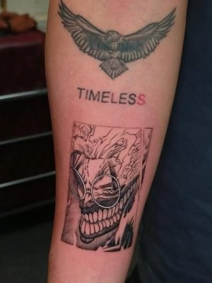 This anime tattoo features a sinister character with sharp teeth, fiery aura, and intense expres